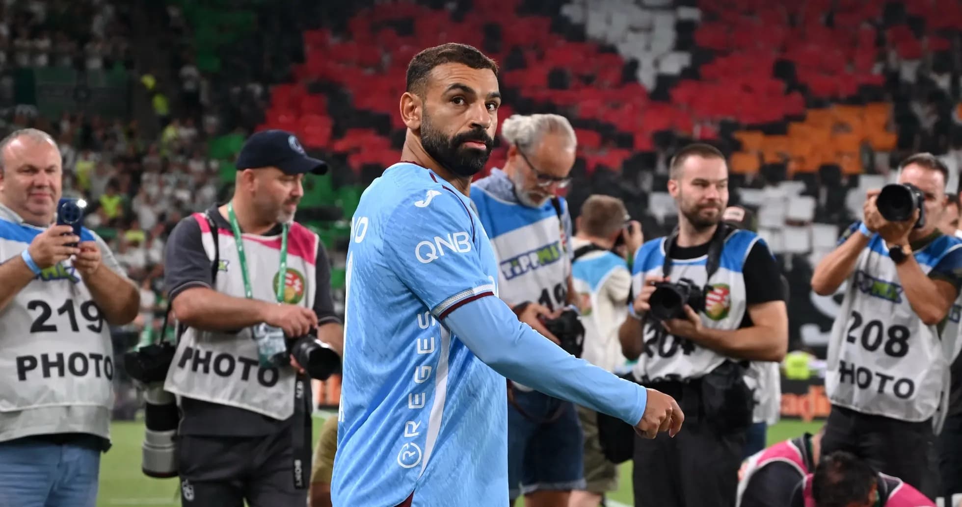 Joueur avec maillot bleu passant devant des photographes