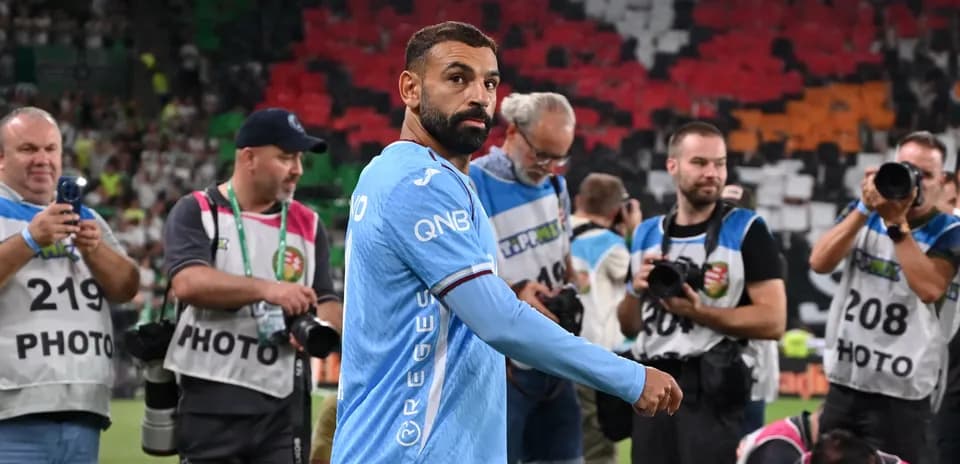 Joueur avec maillot bleu passant devant des photographes
