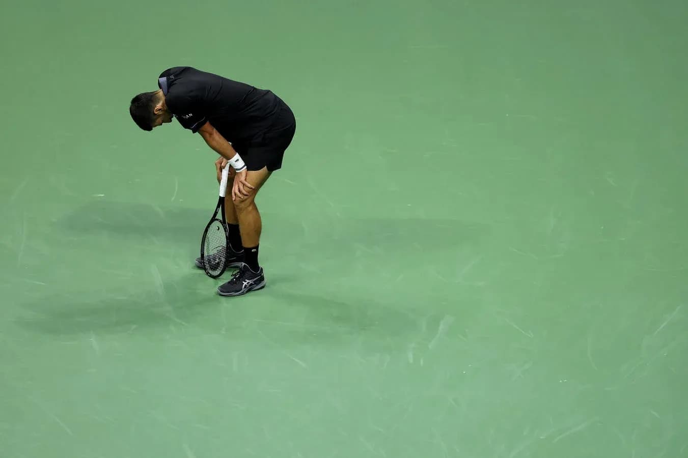 Joueur de tennis penché sur le court vert