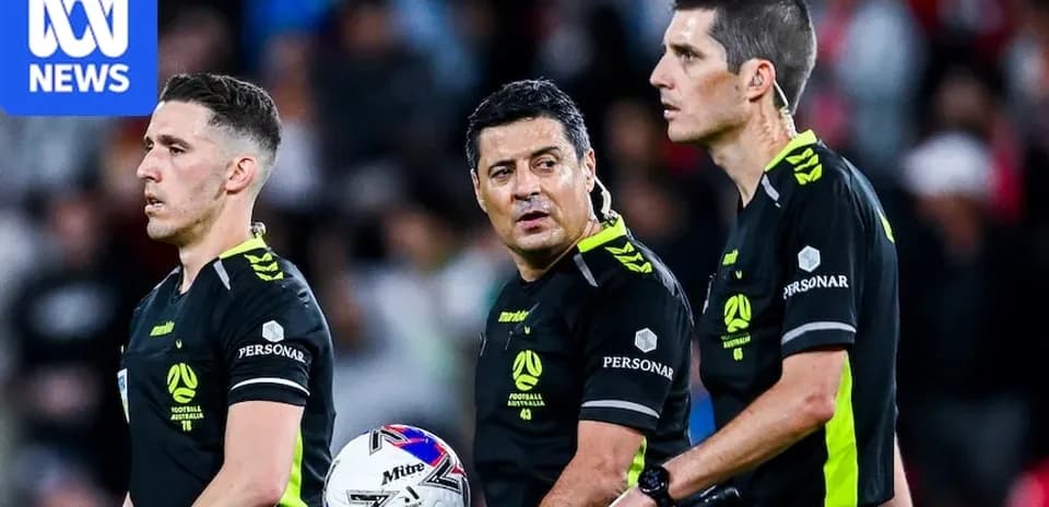 Trois arbitres discutant sur le terrain de football