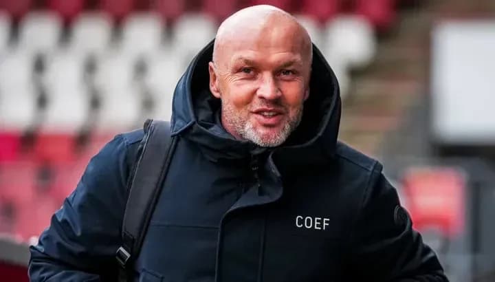 Homme souriant portant un manteau à l'entrée du stade