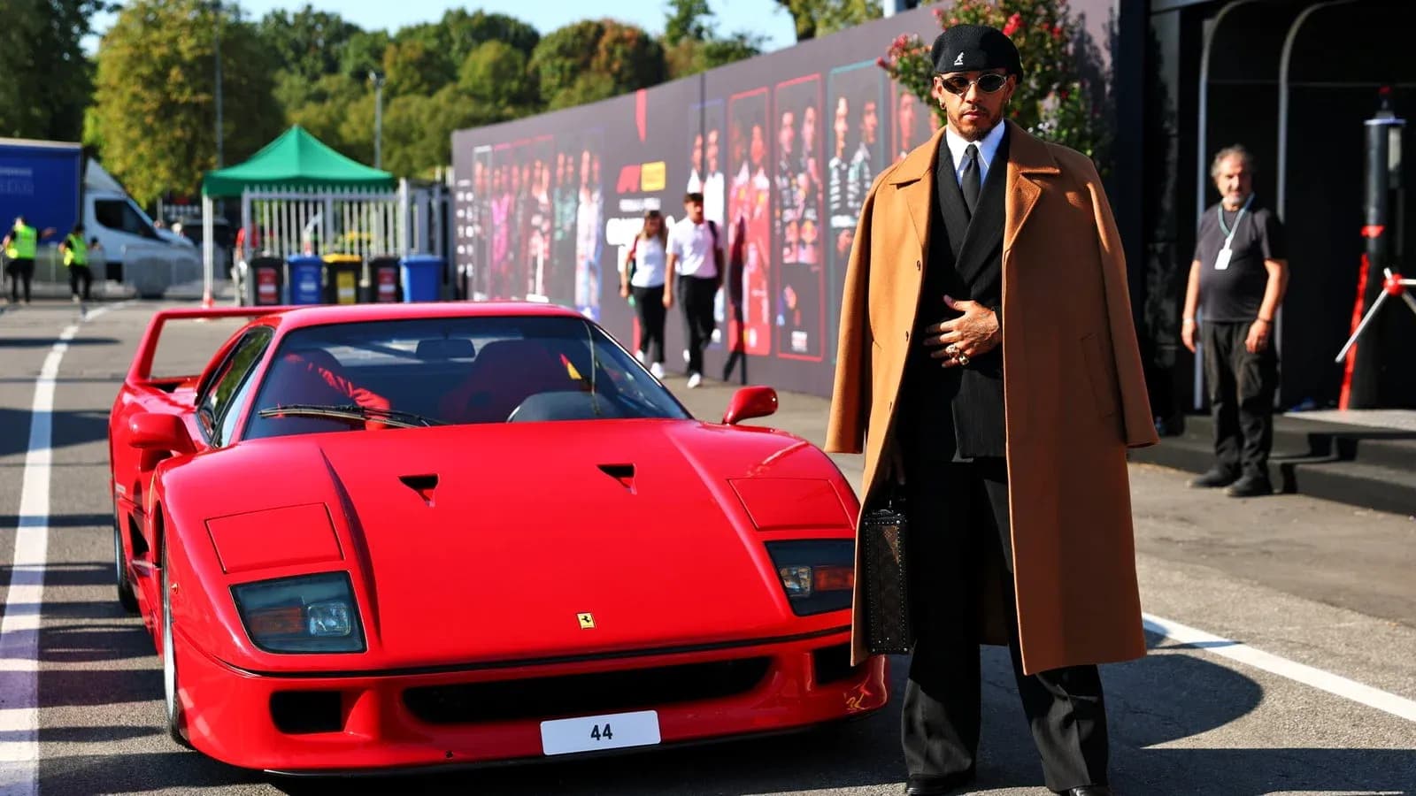 Homme en costume devant une Ferrari rouge