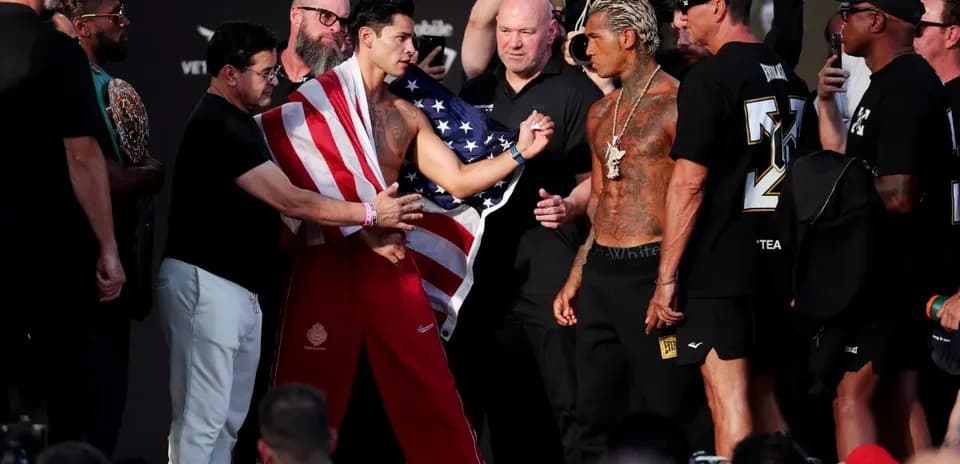 Boxers facing off at weigh-in with crowd present