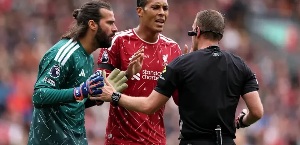 Joueurs de Liverpool discutant avec l'arbitre pendant un match