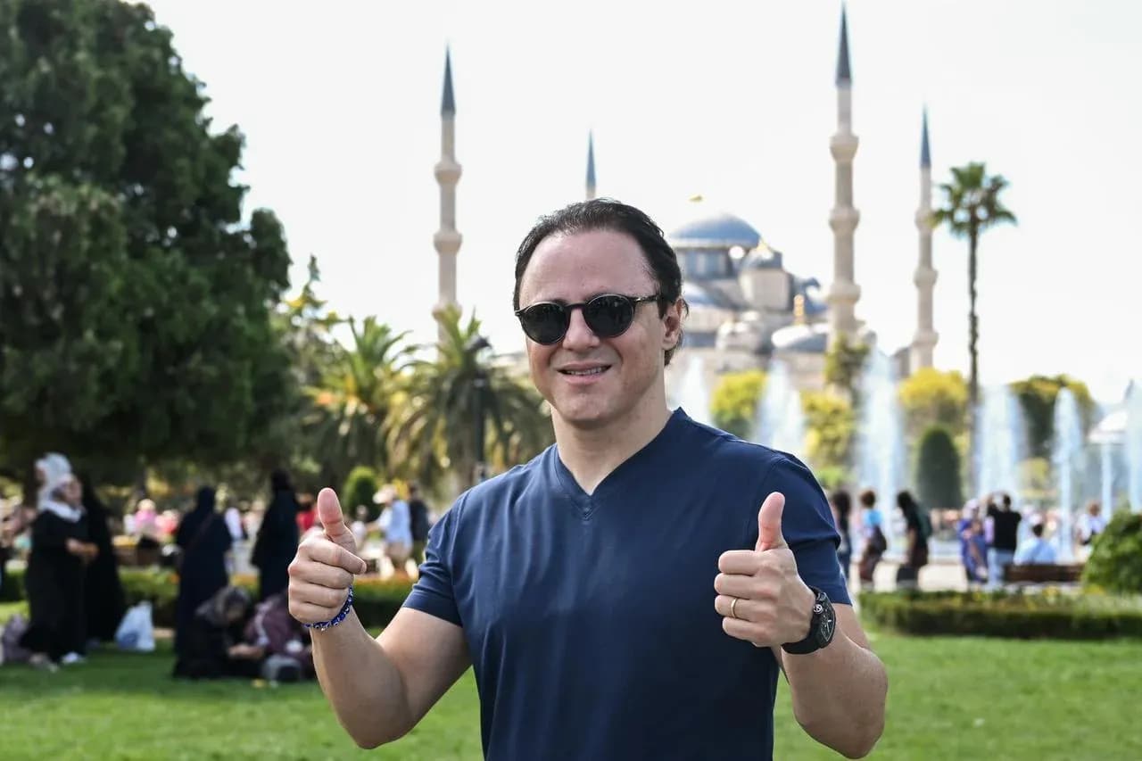 Homme souriant avec pouces levés devant la mosquée
