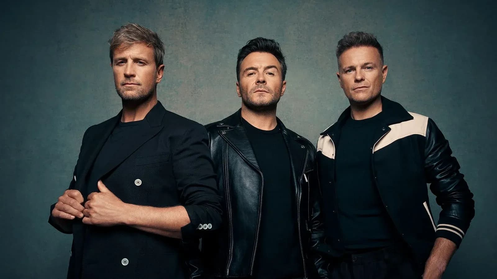 Trois hommes posant ensemble sur fond texturé
