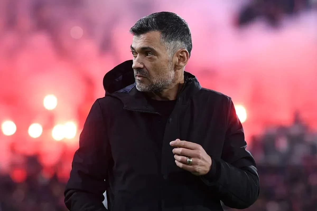 Entraîneur observant le match avec fumigènes en arrière-plan