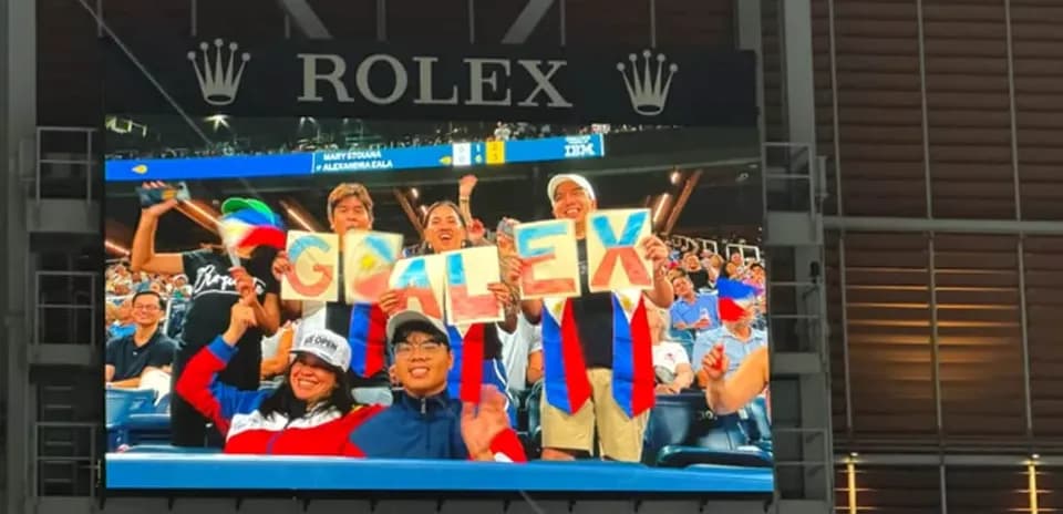 Supporters holding 'GO ALEX' signs in stadium