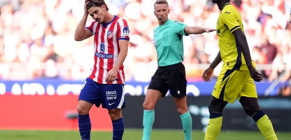Joueur d'Atlético se tenant la tête, arbitre en arrière-plan