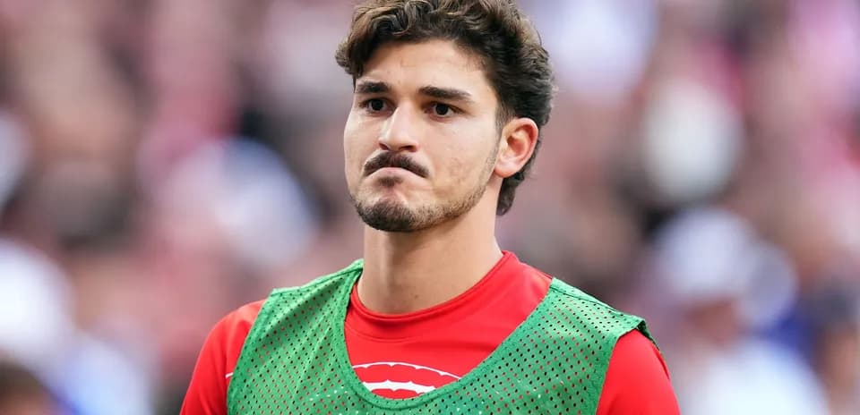 Joueur en attente sur le banc, maillot rouge et gilet vert