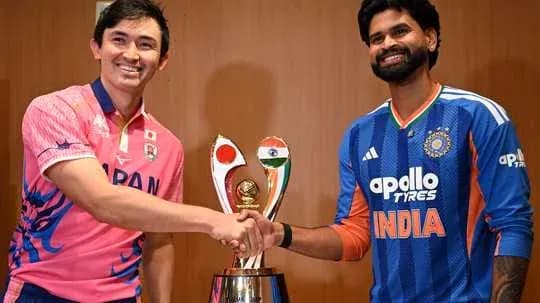Joueurs de Japon et d'Inde serrant la main devant le trophée