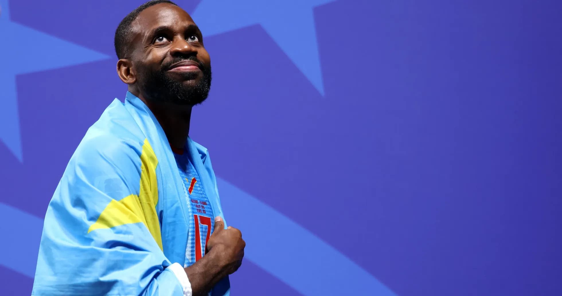 Athlete wearing national flag, looking upward