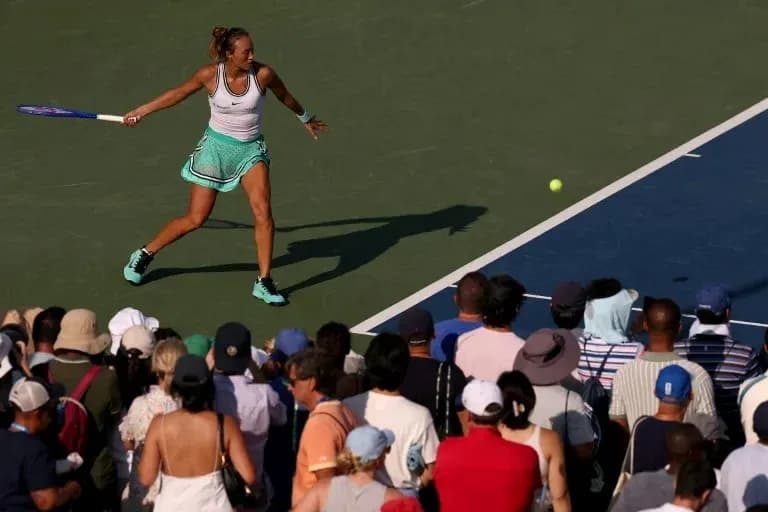 Joueuse de tennis frappant la balle devant un public