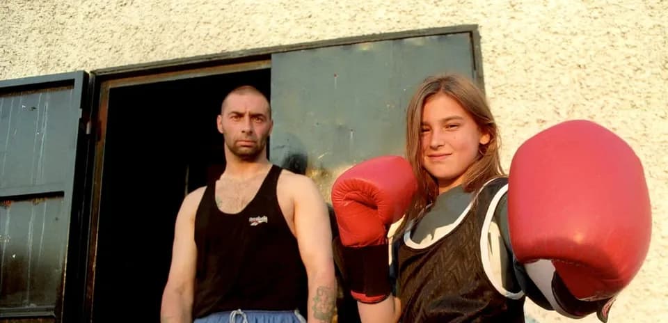Fille avec des gants de boxe et un homme en arrière-plan