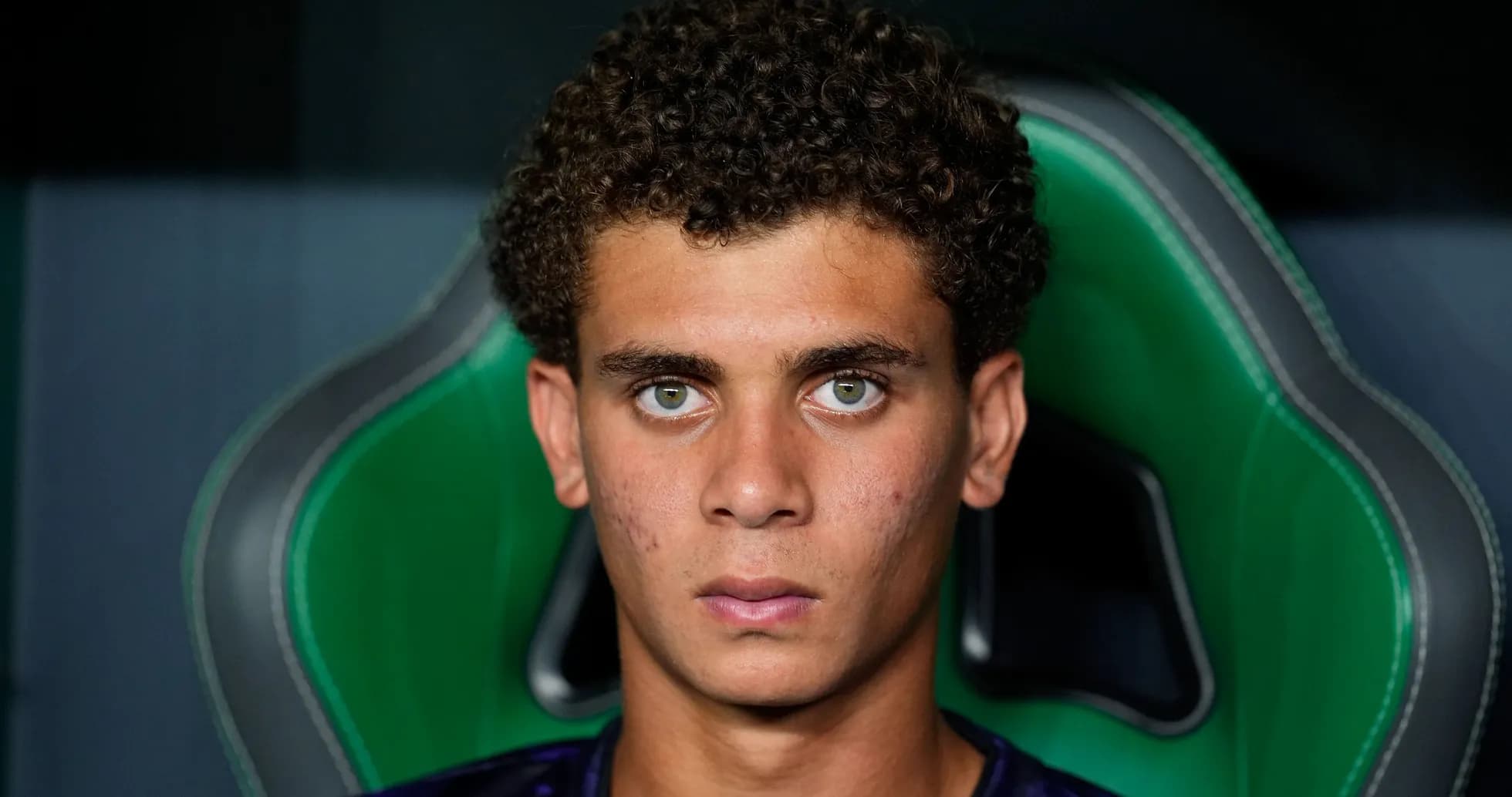 Jeune joueur assis sur un fauteuil vert