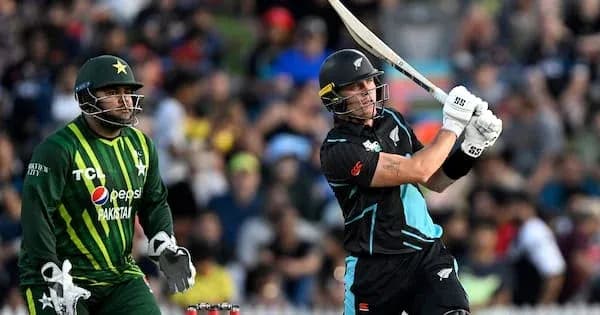 Batsman hitting ball while wicketkeeper observes