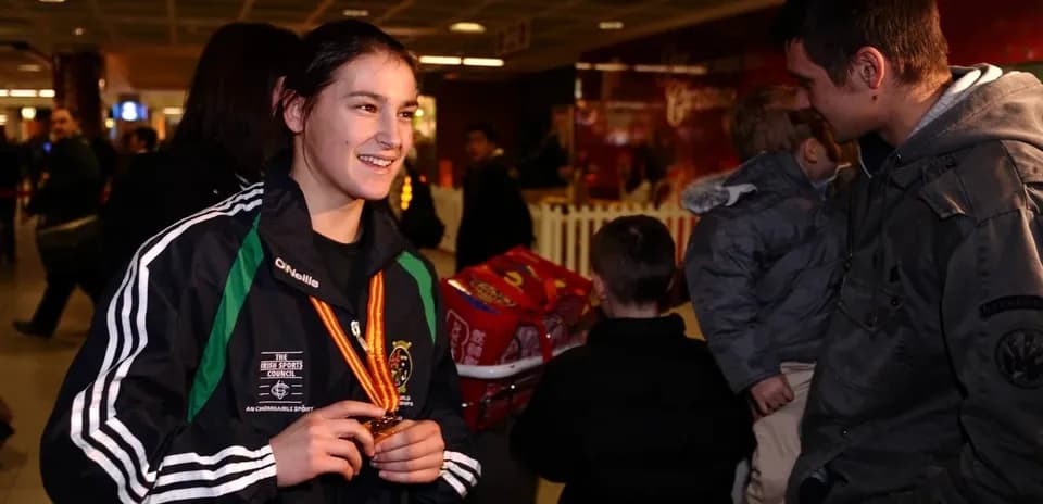 Athlete holding medal in busy airport terminal