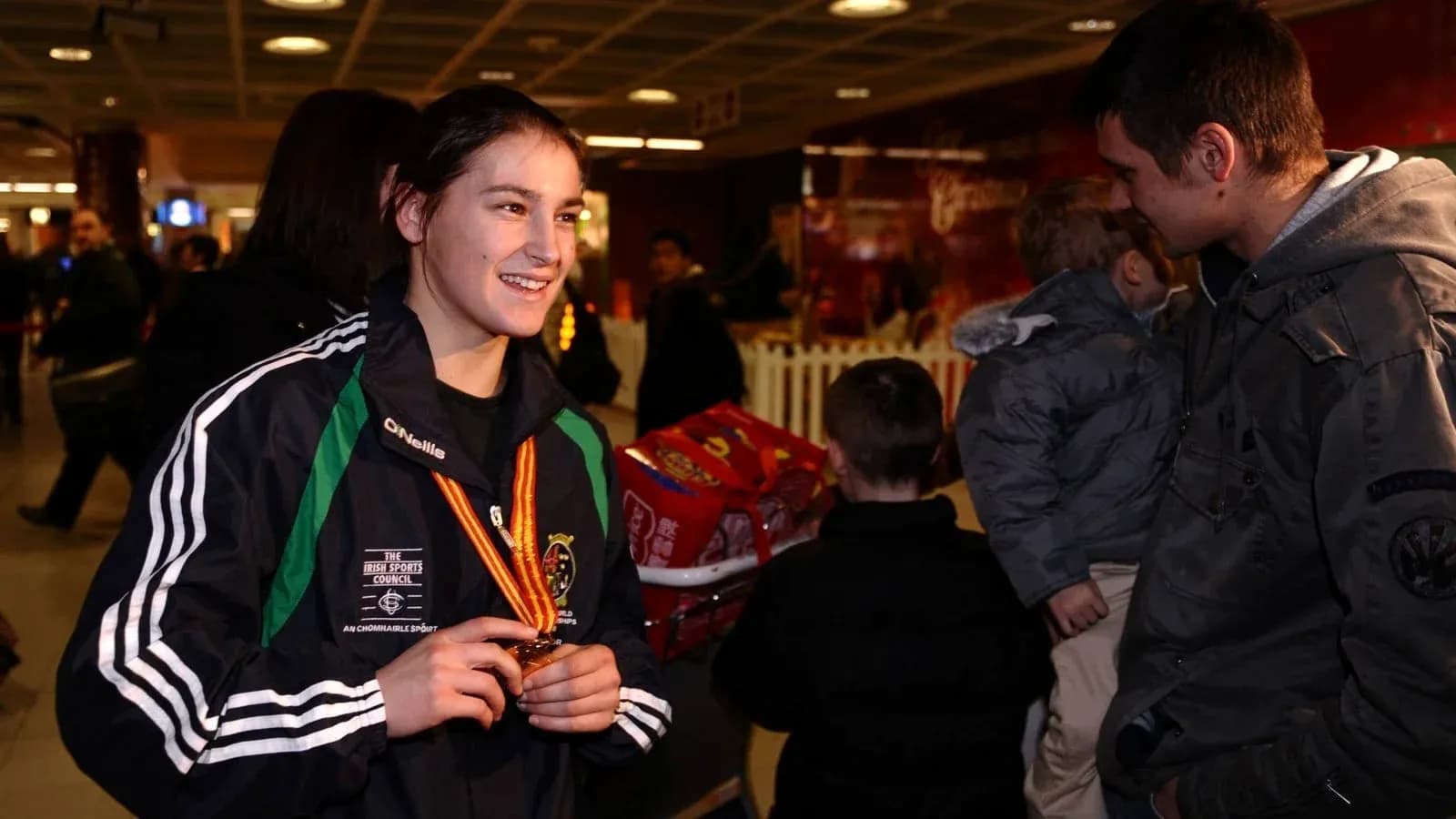 Athlete holding medal in busy airport terminal