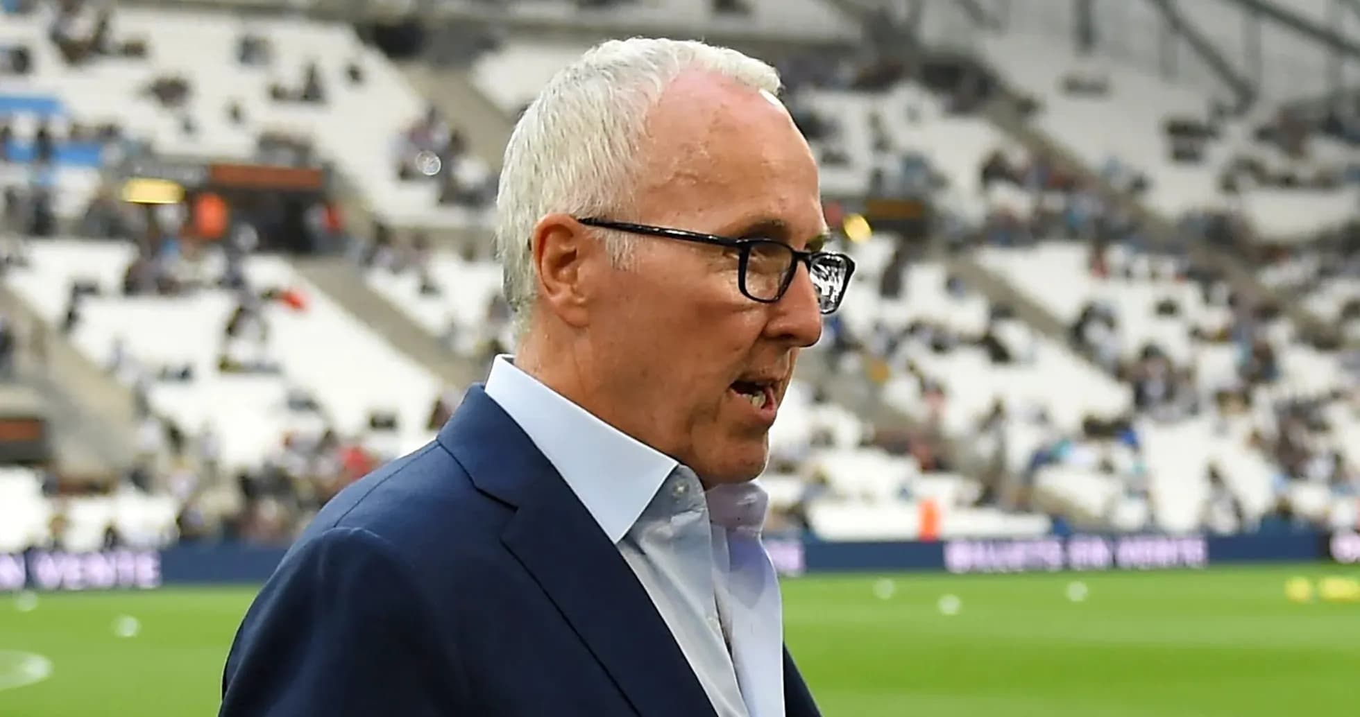 Homme en costume marchant près du terrain de football
