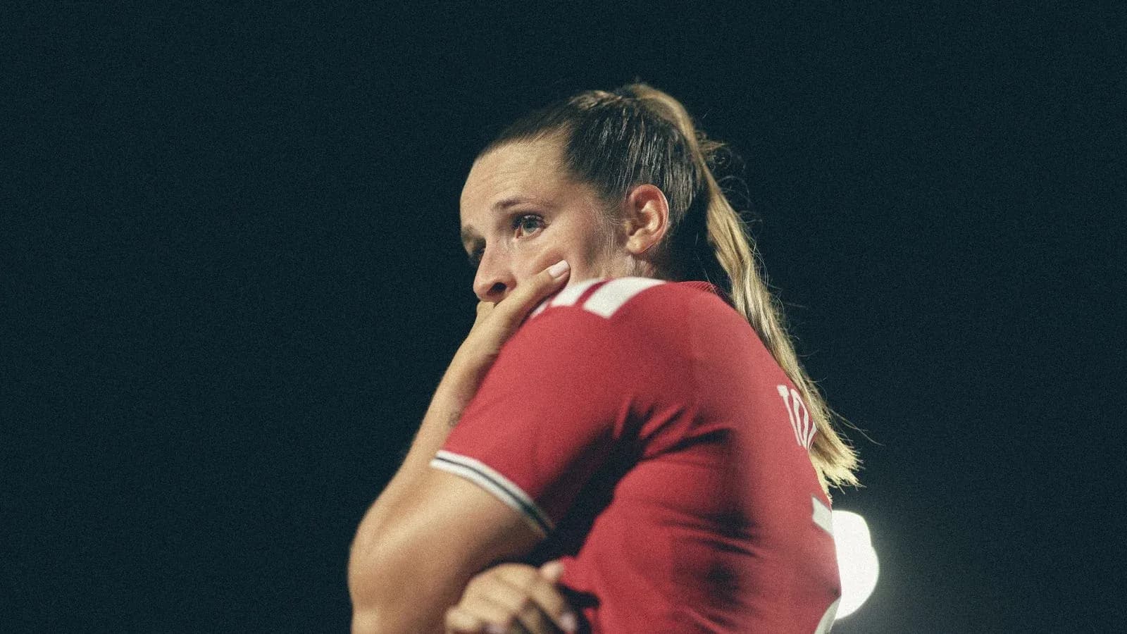 Joueuse de football en maillot rouge, pensive