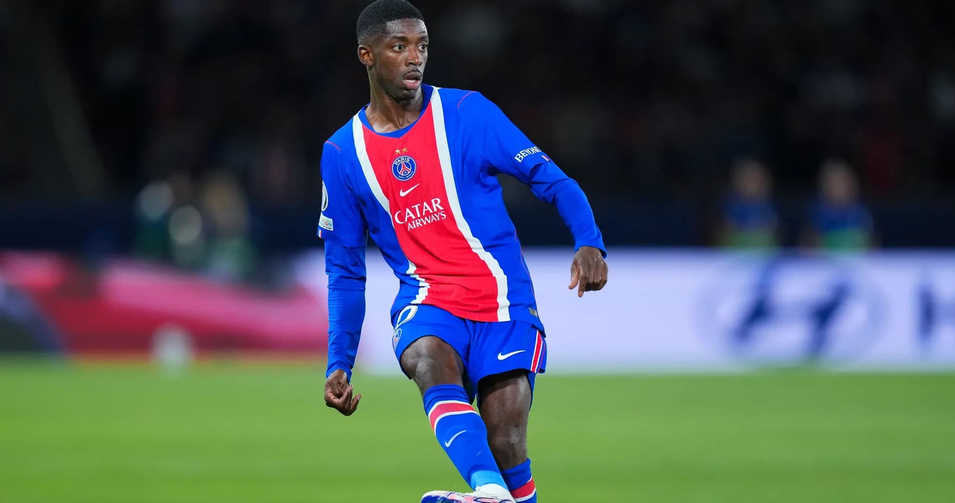 Joueur du PSG dribblant sur le terrain de football