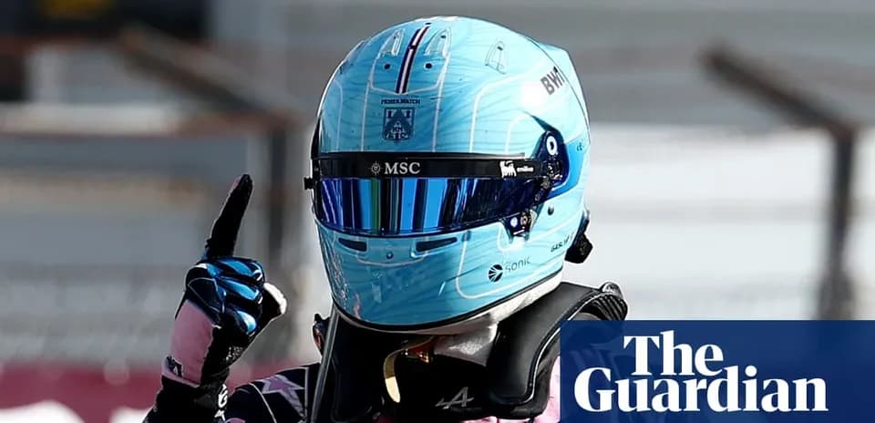 Pilote de Formule 1 portant un casque bleu levant un doigt