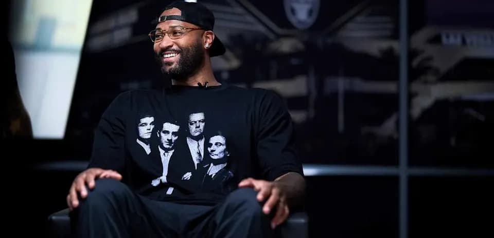 Homme souriant portant un t-shirt noir assis