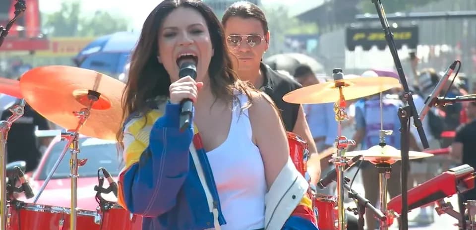 Chanteuse performe sur scène avec batteur en arrière-plan