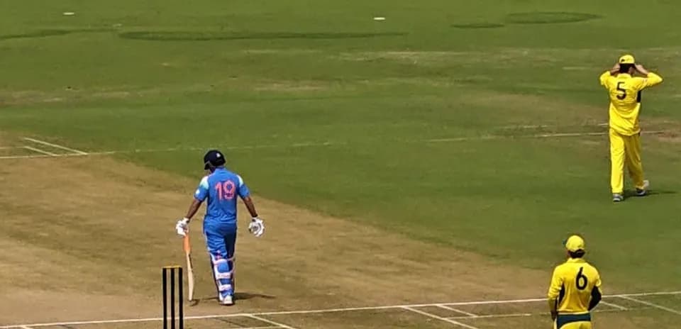 Batsman in blue uniform walking to the crease