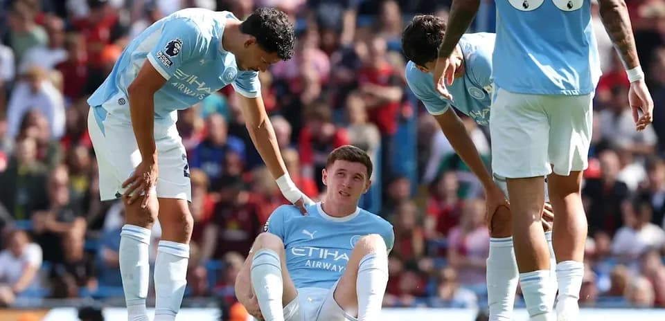 Joueur de Manchester City assis, blessé, entouré de coéquipiers