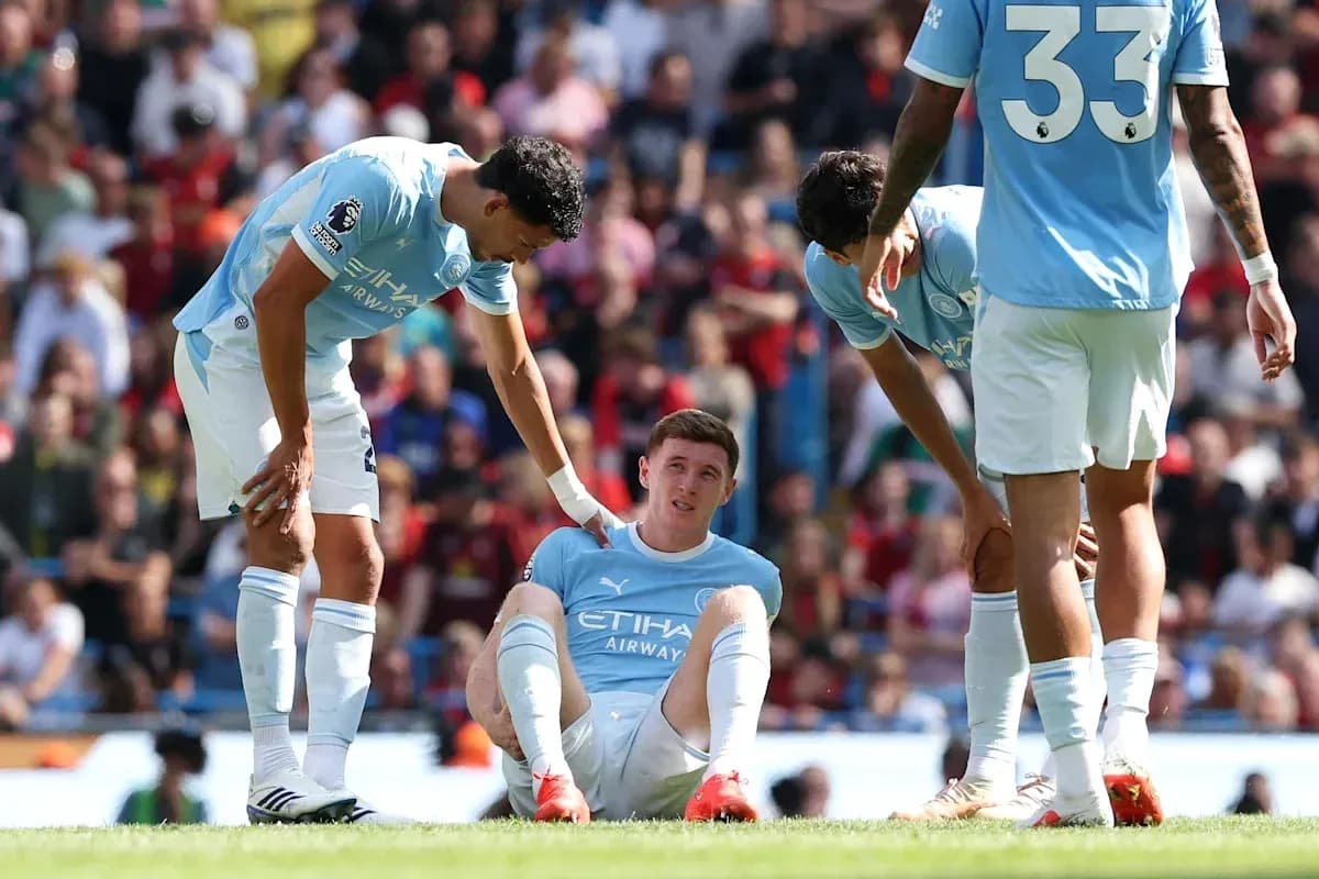 Joueur de Manchester City assis, blessé, entouré de coéquipiers
