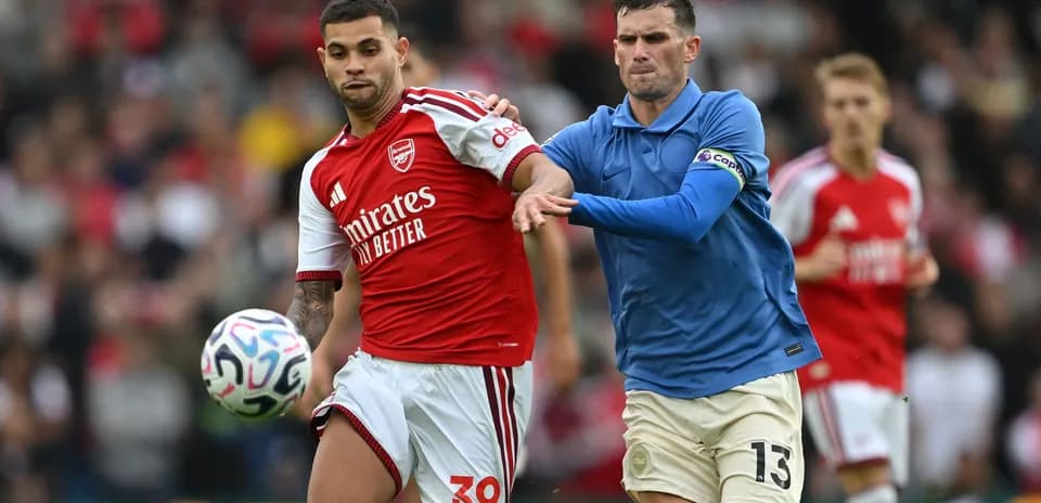 Joueur d'Arsenal dribblant sous la pression d'un adversaire
