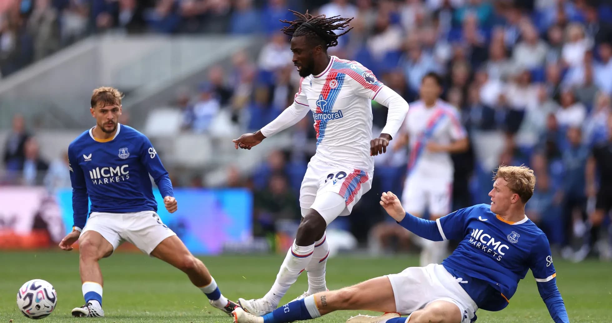 Joueur de Crystal Palace dribblant deux adversaires d'Everton