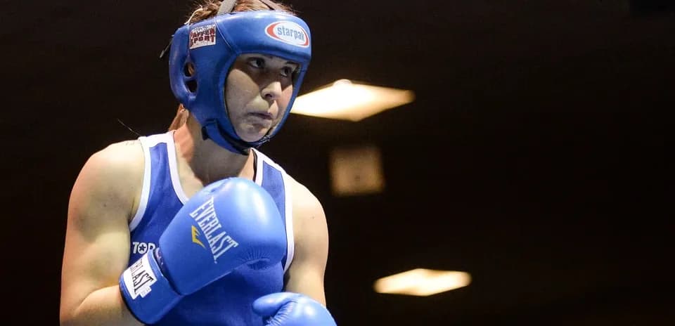Boxeuse en action avec gants bleus sur le ring