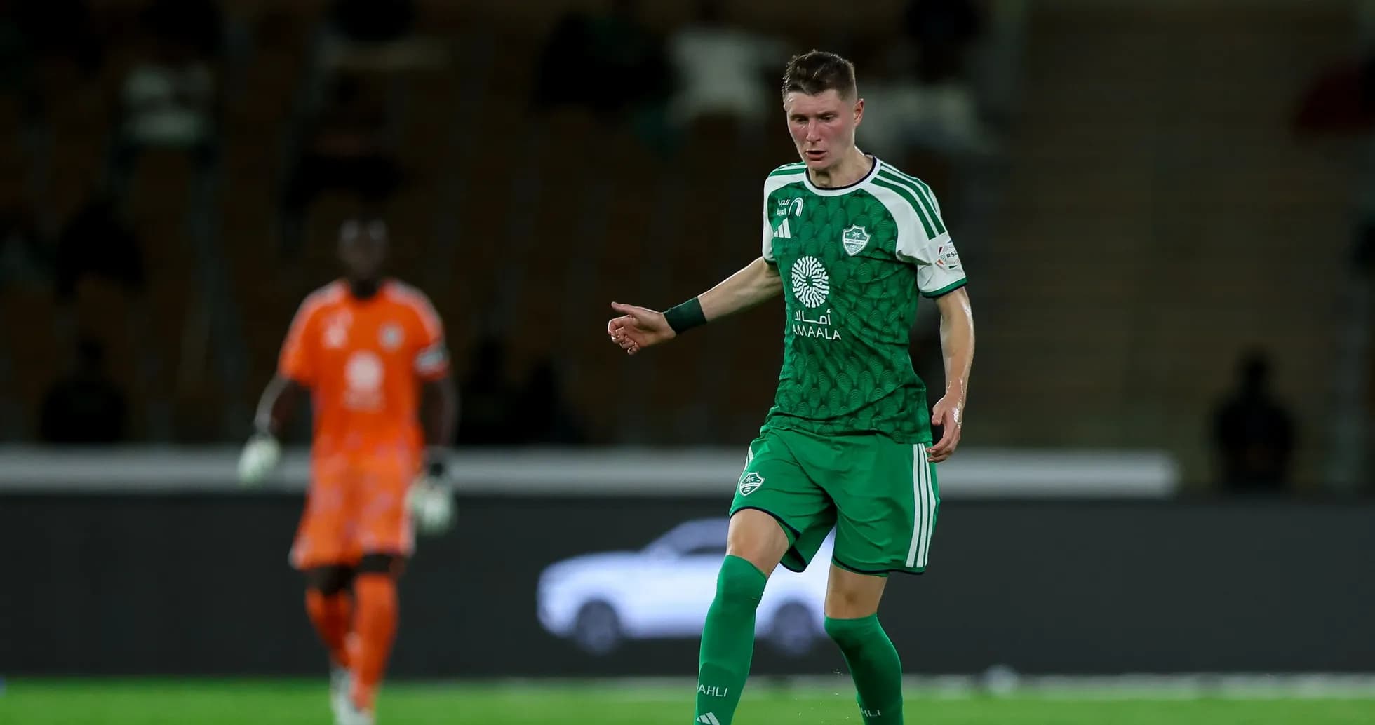 Joueur en maillot vert dribblant sur le terrain de football Joueur en maillot vert dribblant sur le terrain de football